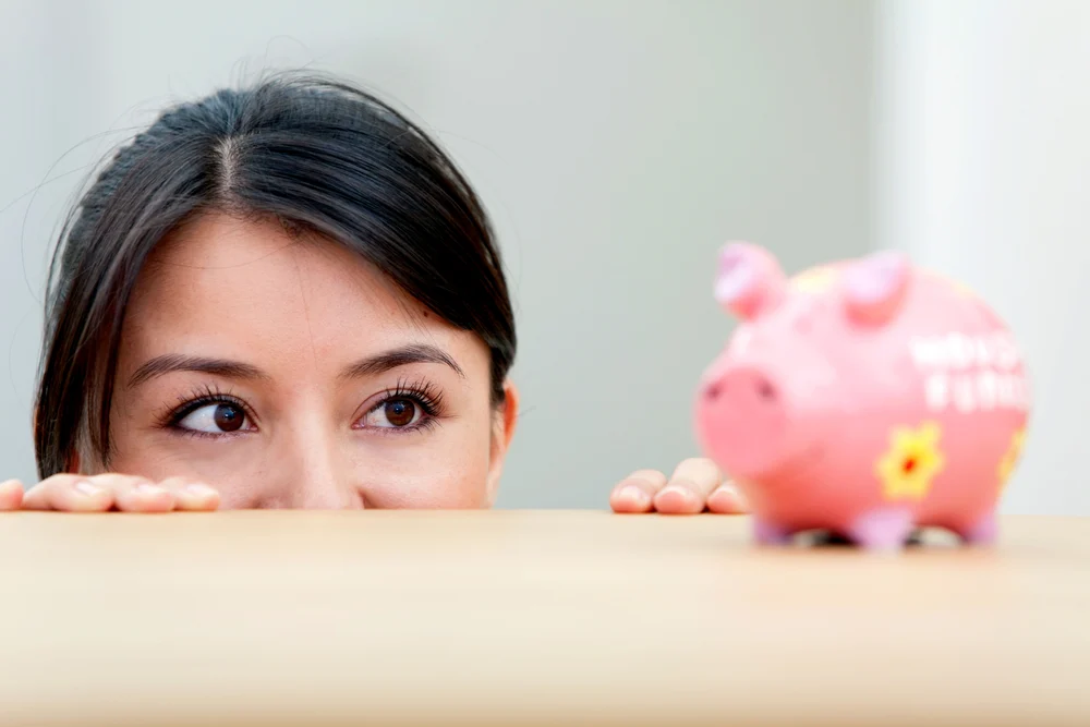 Beautiful woman looking at her savings in a piggybank